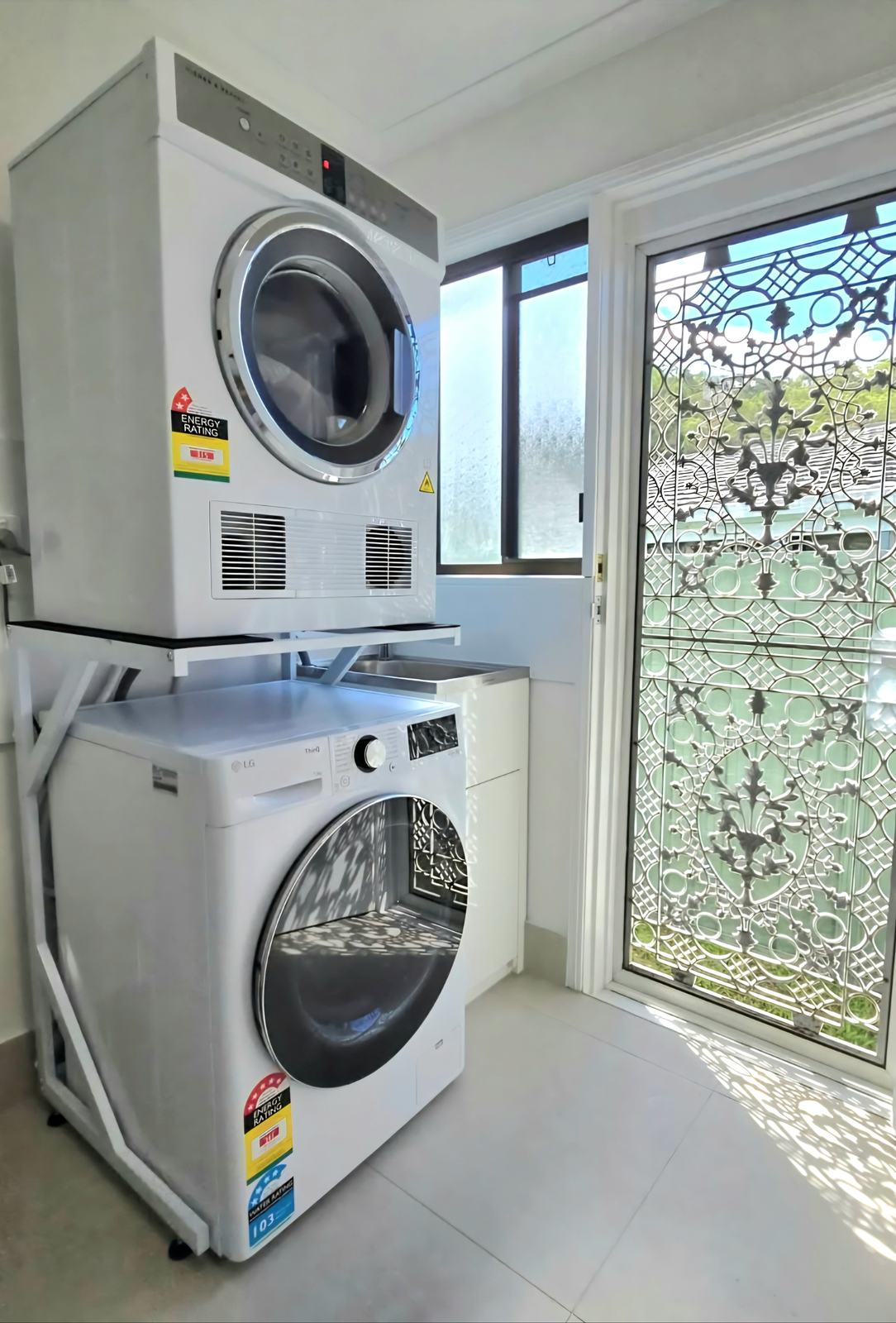 Real Space DryerStand Maxi showing a DryerStand freestanding tumble dryer stand in a real laundry space with a dryer above a washing machine