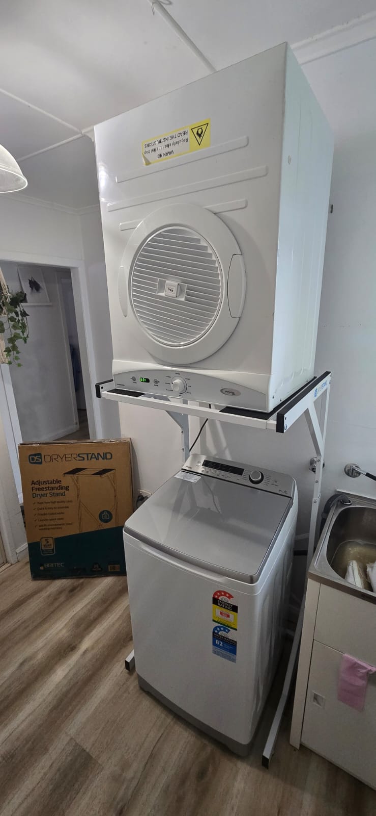 Real Space DryerStand Adjustable showing a DryerStand freestanding tumble dryer stand in a real laundry space with a dryer above a washing machine