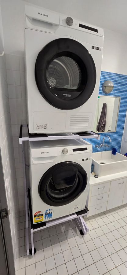 Real Space DryerStand Maxi showing a DryerStand freestanding tumble dryer stand in a real laundry space with a dryer above a washing machine