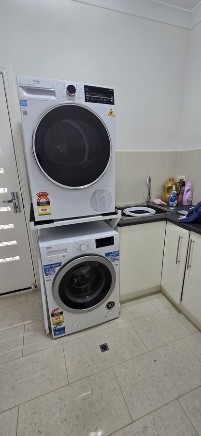 Real Space DryerStand Maxi showing a DryerStand freestanding tumble dryer stand in a real laundry space with a dryer above a washing machine