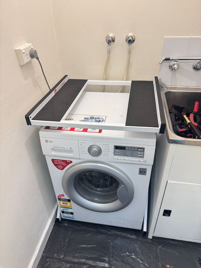 Real Space DryerStand Maxi showing a DryerStand freestanding tumble dryer stand in a real laundry space with a dryer above a washing machine