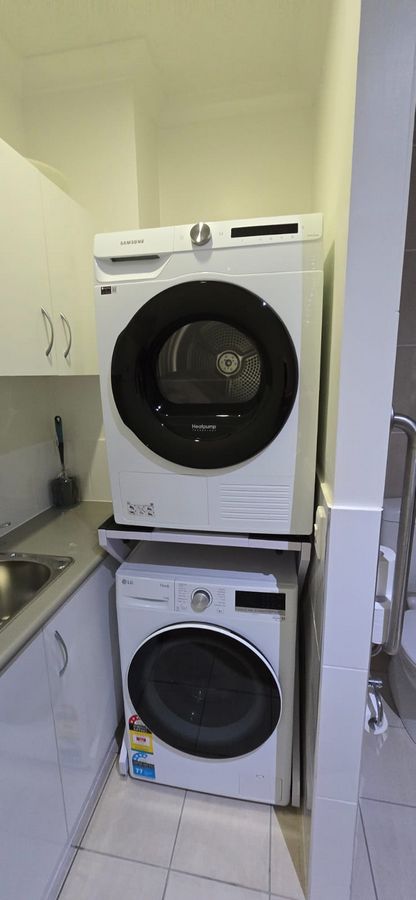Real Space DryerStand Maxi showing a DryerStand freestanding tumble dryer stand in a real laundry space with a dryer above a washing machine