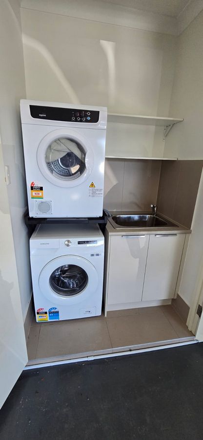 Real Space DryerStand Maxi showing a DryerStand freestanding tumble dryer stand in a real laundry space with a dryer above a washing machine