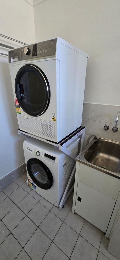 Real Space DryerStand Maxi showing a DryerStand freestanding tumble dryer stand in a real laundry space with a dryer above a washing machine