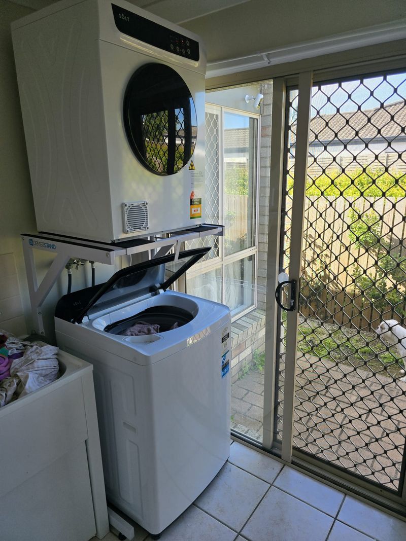 Real Space DryerStand Adjustable showing a DryerStand freestanding tumble dryer stand in a real laundry space with a dryer above a washing machine