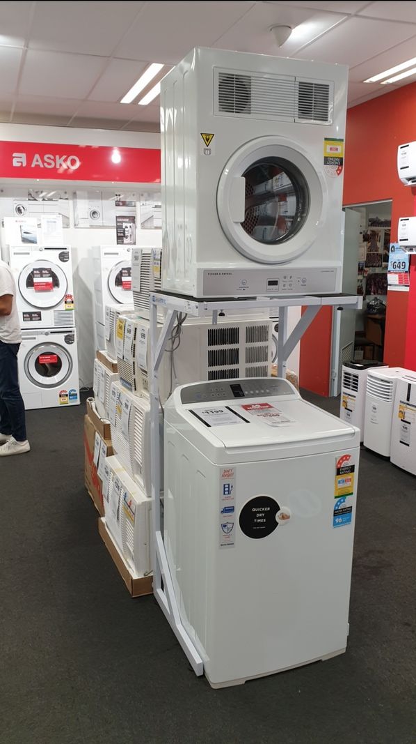 Real Space DryerStand Maxi showing a DryerStand freestanding tumble dryer stand in a real laundry space with a dryer above a washing machine