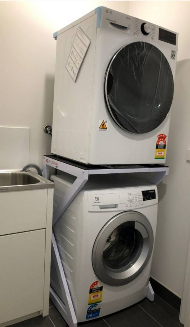 Real Space DryerStand Maxi showing a DryerStand freestanding tumble dryer stand in a real laundry space with a dryer above a washing machine