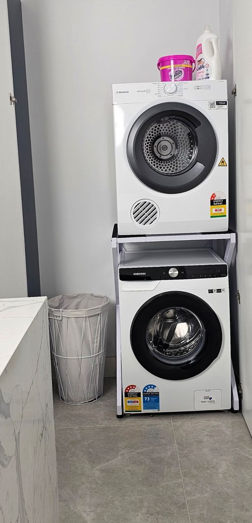 Real Space DryerStand Maxi showing a DryerStand freestanding tumble dryer stand in a real laundry space with a dryer above a washing machine