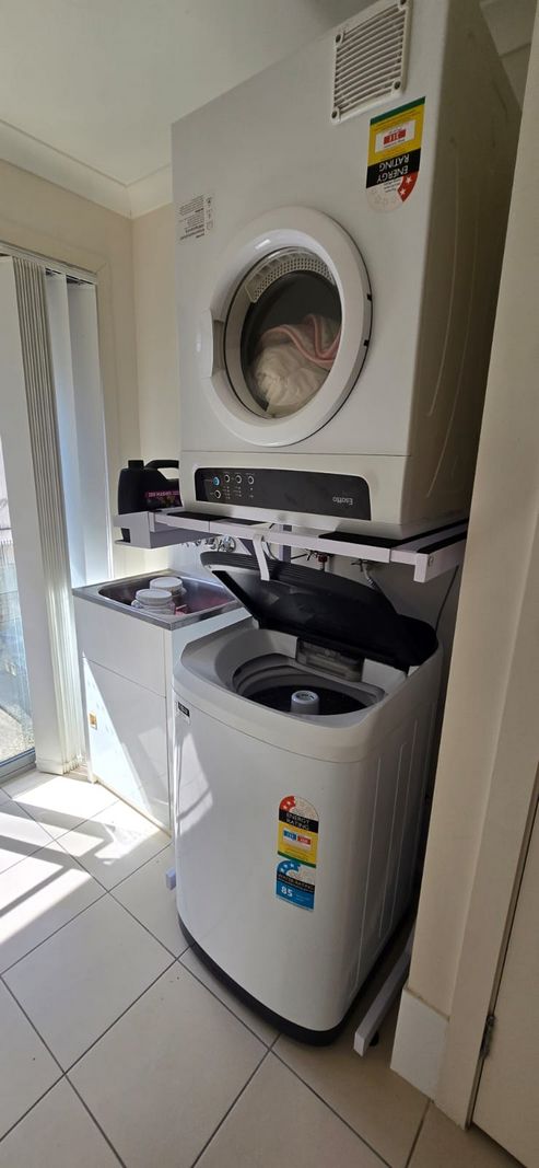 Real Space DryerStand Adjustable showing a DryerStand freestanding tumble dryer stand in a real laundry space with a dryer above a washing machine