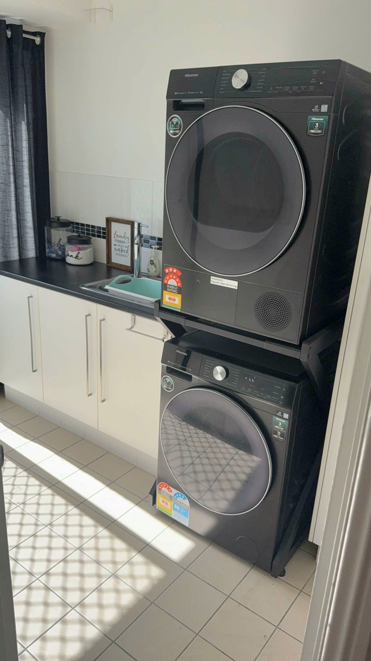 Real Space DryerStand Maxi showing a DryerStand freestanding tumble dryer stand in a real laundry space with a dryer above a washing machine
