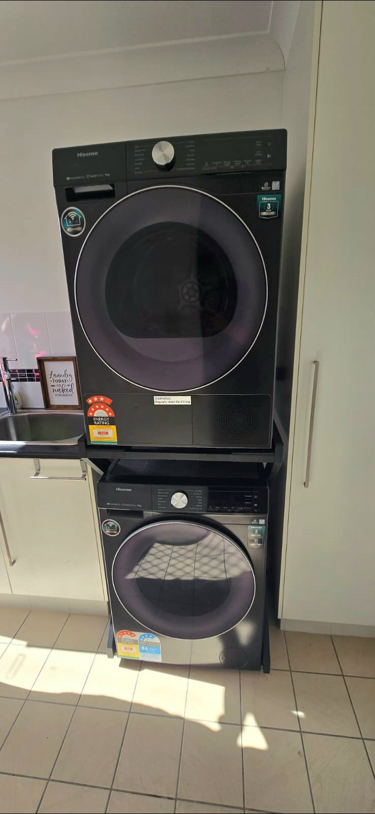Real Space DryerStand Maxi showing a DryerStand freestanding tumble dryer stand in a real laundry space with a dryer above a washing machine